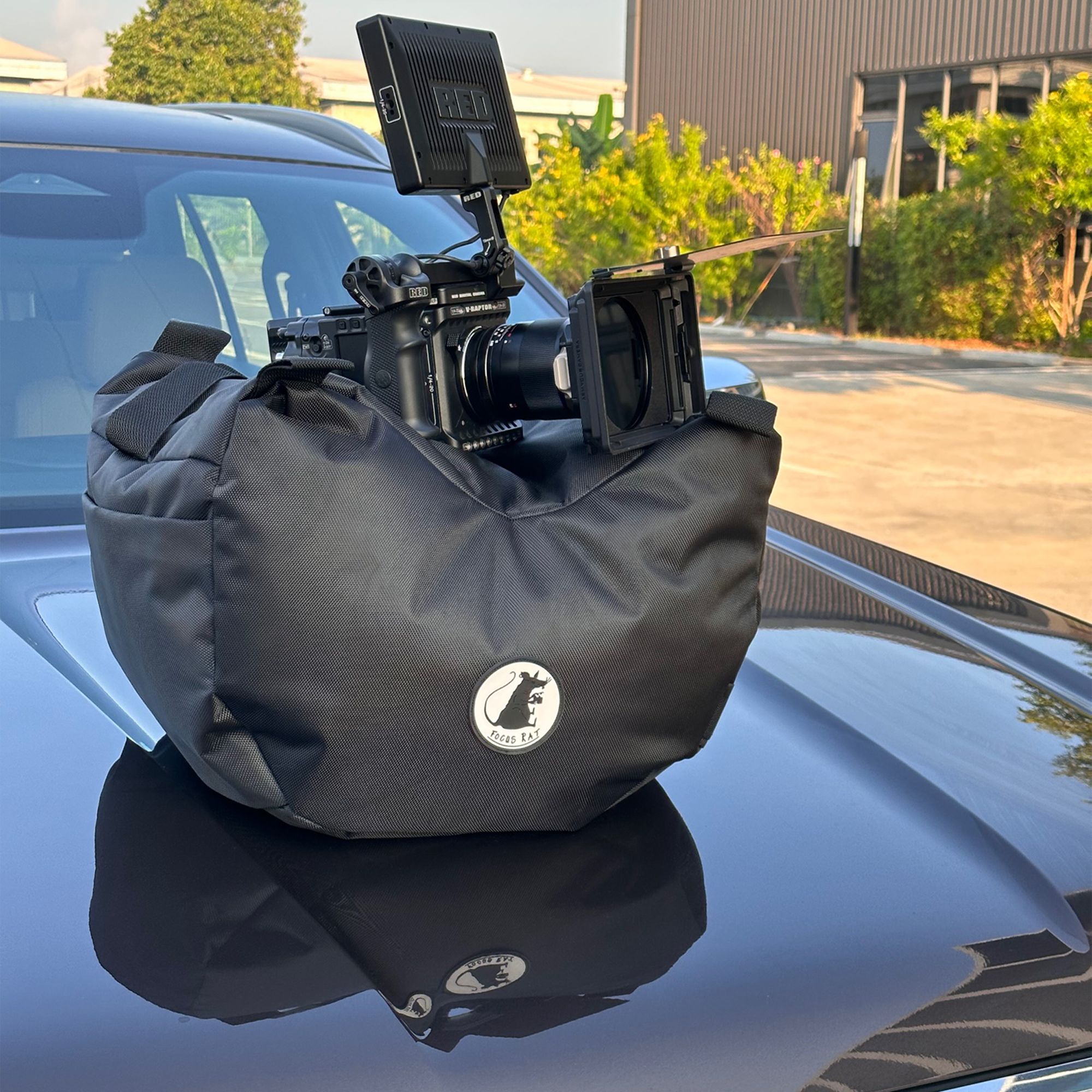 Customizable Professional Steady bag (Steady Saddle) Large Bag True Black with a red camera on top, and the whole setup on the hood of a nice car